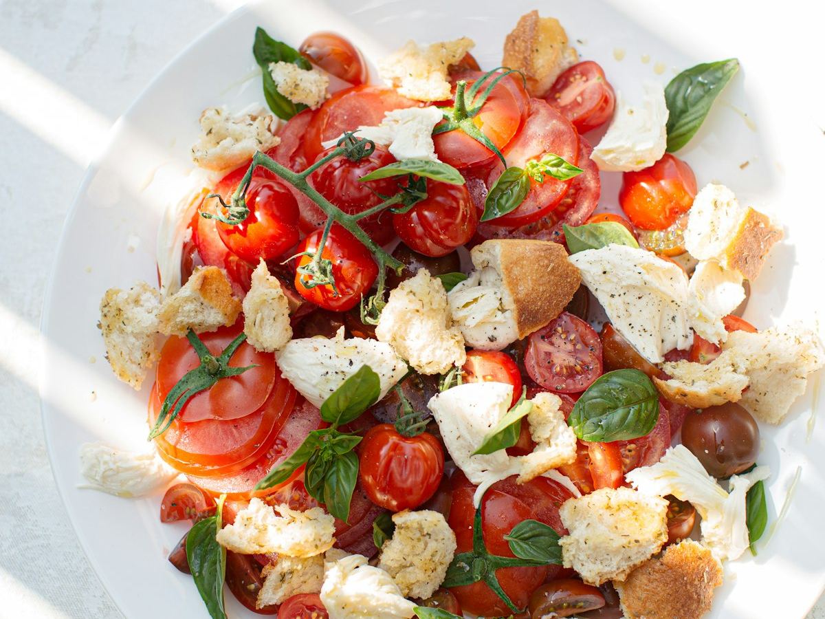 Fresh tomatoes, herbs and cheese laid out on a plate