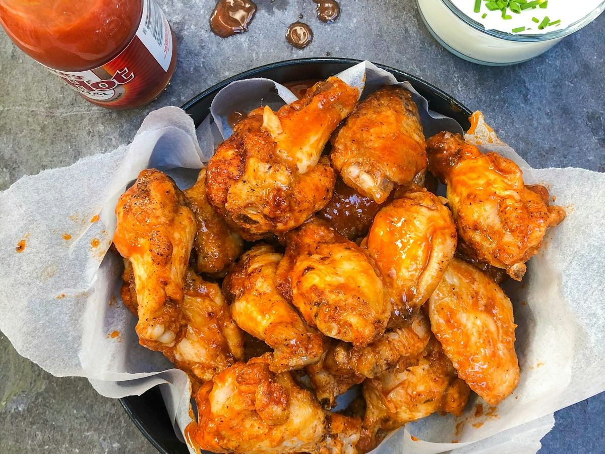 Basket of glazed hot chicken wings with dip